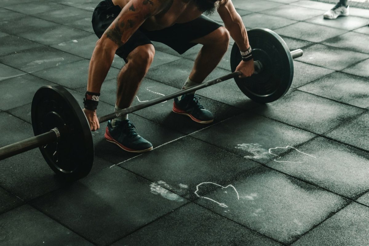 Athlète en position de départ d'un soulevé de terre sur une barre chargée, dans une box CrossFit